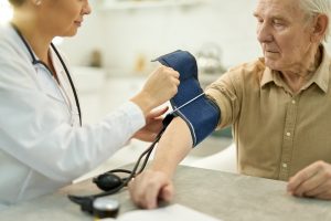 Aged man with manometer cuff around his arm