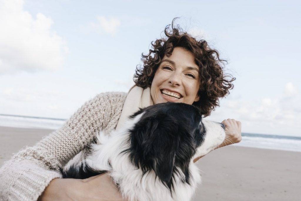 Happy woman with dog on the beach