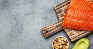 Food sources of healthy unsaturated fat and omega 3: fresh raw salmon fillet, avocado, olives, nuts