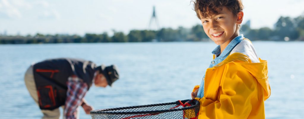 Handsome boy smiling while fishing with grandfather