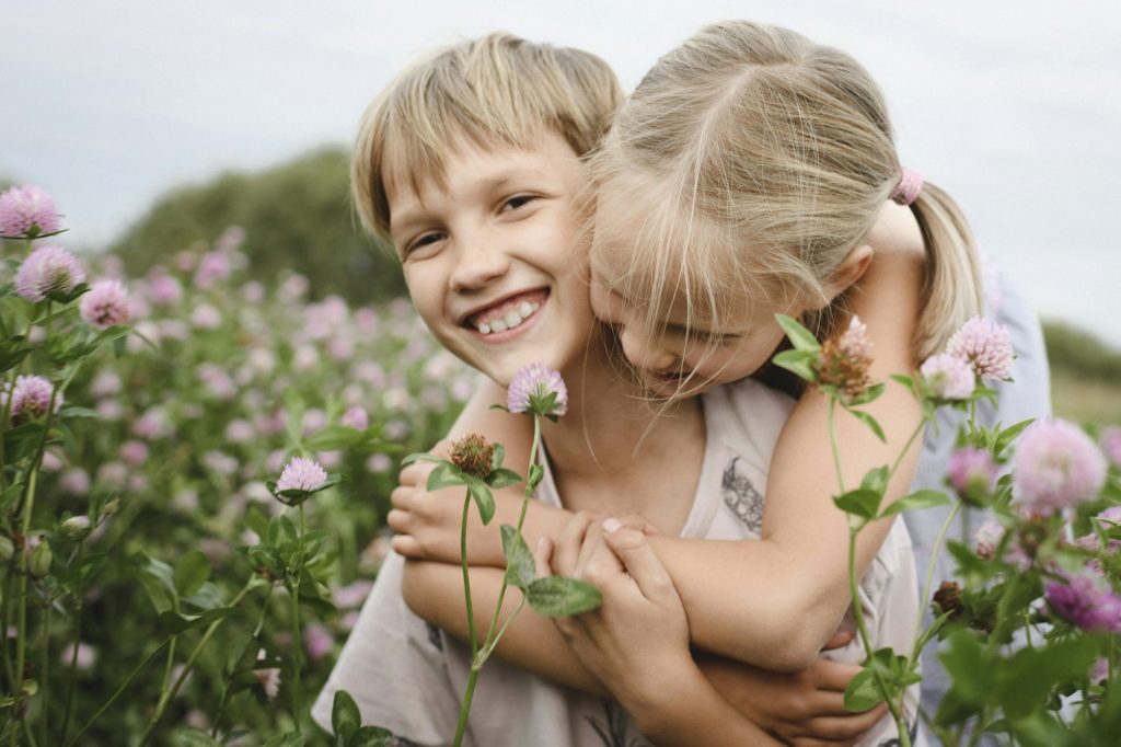 Two smiling children on clover field
