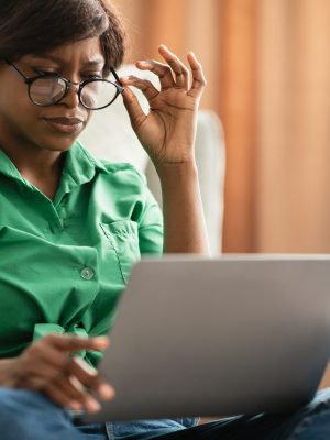 Black Woman With Poor Eyesight Using Laptop Wearing Eyeglasses Indoor